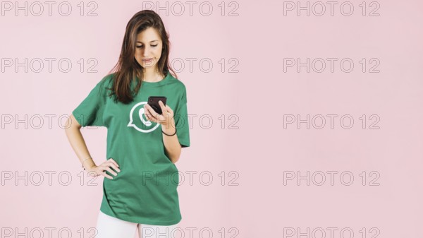 Sad young woman using mobile phone against pink backdrop