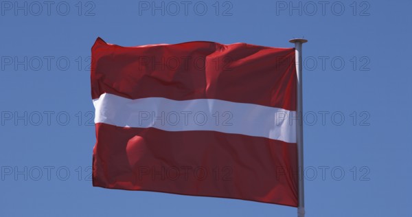 Latvian Flag Waving in the Wind against blue sky
