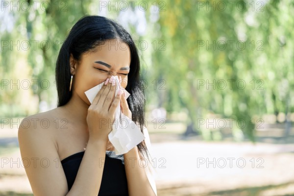 African american woman blows her nose into a tissue. allergy, disease, illness concept