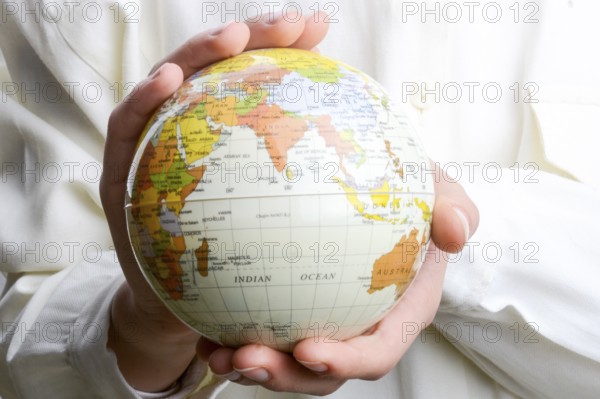Child holding a small model globe in hand on white background