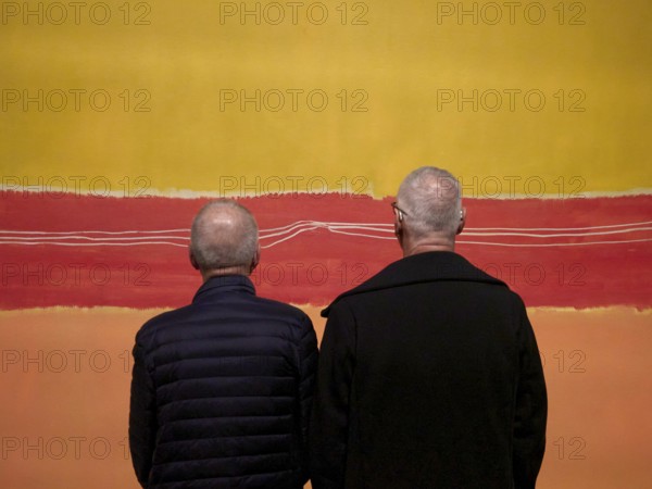 Two men looking at an abstract painting with yellow and red stripes, Fondation Luis Vuitton. Paris