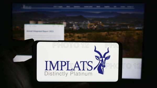 Stuttgart, Germany, 12-07-2023: Person holding cellphone with logo of company Impala Platinum Holdings Limited (Implats) in front of business webpage. Focus on phone display, Europe