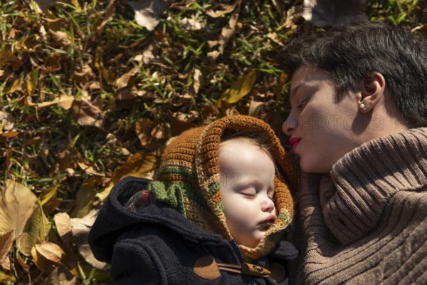 Mother and baby sleeping in the park on autumn leaves