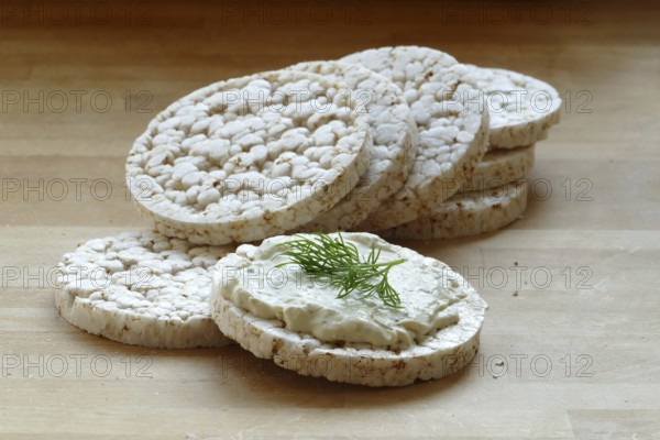 Group of rice cakes, one with cream cheese and herbs on a wooden board