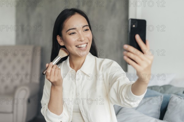 Smiley woman vlogging with make up brush
