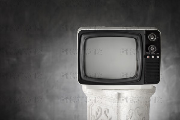 Old portable television on a plaster column