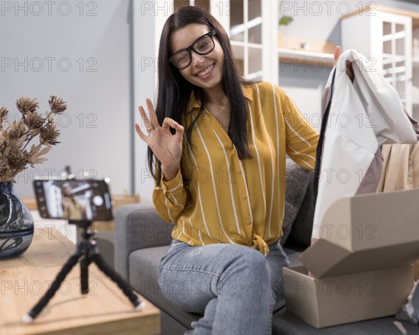 Vlogger home unboxing clothes with smartphone