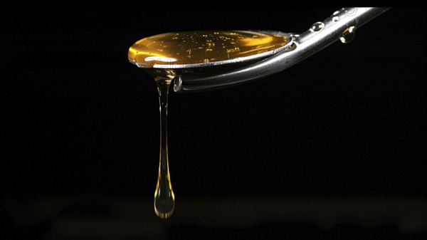 Honey Flowing from Spoon against Black Background