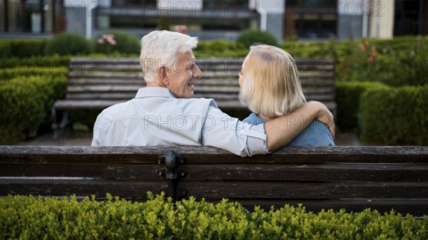 Back view embraced older couple outdoors bench
