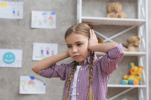 Portrait sad girl covering her ears with two hands