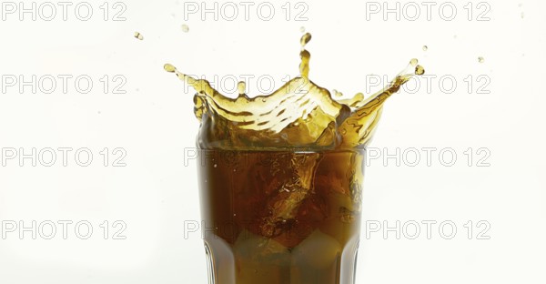 Ice Cubes Falling into Glass of Coke against White Background