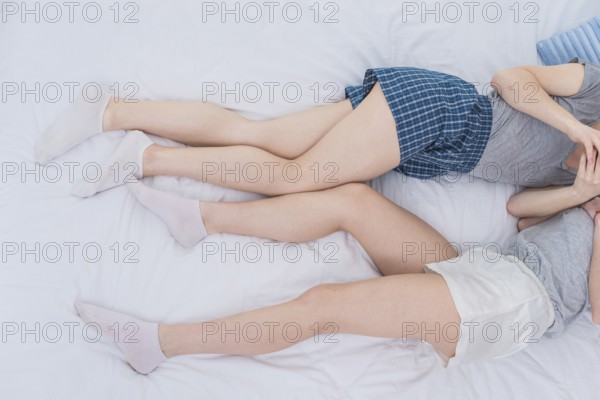 Overhead view two lesbian couple lying white bed