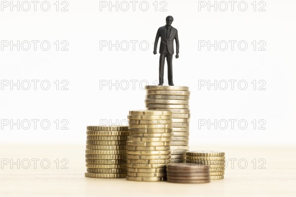 Wealth, making money, wage growth concept. Businessman figurine standing on a pile of coins. Copy space