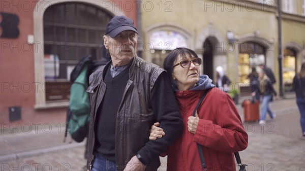 Elderly couple of tourists are walking through the historical center seeing the sights in an old European city. Palace Square, Warsaw Old Town