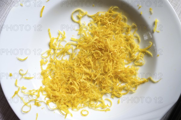 Lemon zest in a white plate, aromatic citrus peel goes well with many dishes and gives a fresh taste, copy space, high angel view from above, selected focus