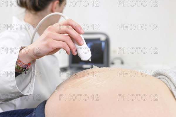 Doctor does Ultrasound or Sonogram Procedure to a Pregnant Woman in the Hospital, Close-up Shot of the Obstetrician Moving Transducer on the Belly of the Future Mother