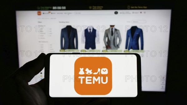 Stuttgart, Germany, 03-18-2023: Person holding smartphone with logo of US online shop company Temu on screen in front of website. Focus on phone display, Europe