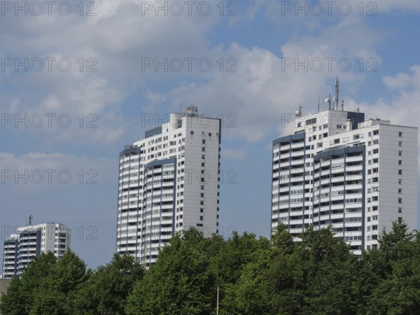 Several tall residential buildings surrounded by trees under a slightly cloudy sky, bremerhaven, bremen, germany