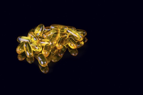 Capsules with fish oil on black background with reflection and copyspace