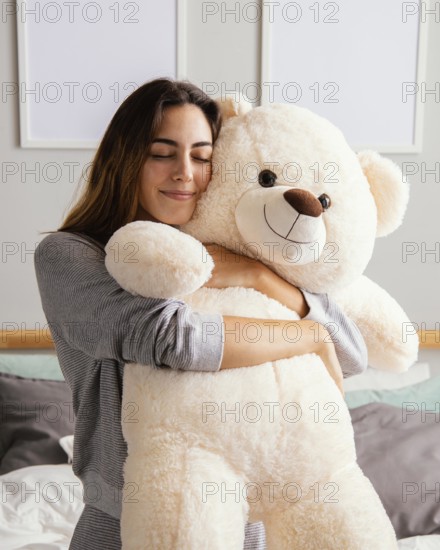 Woman home embracing big teddy bear