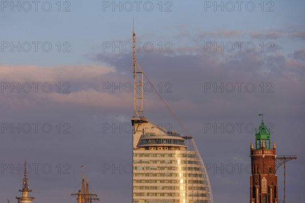 Modern glass buildings and a historic tower at sunset, the sky shows pink clouds, bremerhaven, bremen, germany
