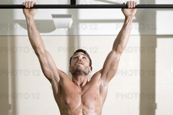 Athlete doing pull-ups at the gym. Handsome man doing functional training. High quality photo
