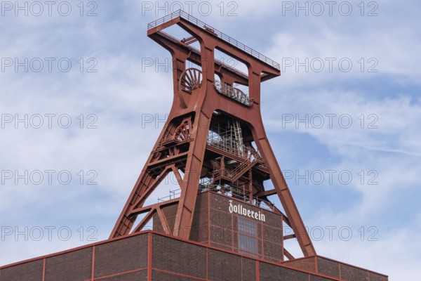 The historic winding tower of the Zeche Zollverein in front of a blue sky with clouds, essen. ruhr area, germany