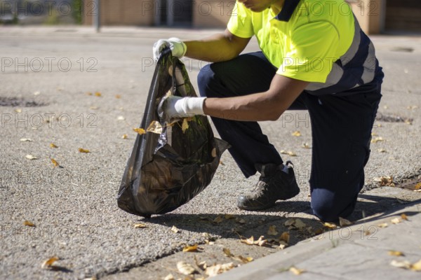 Unrecognizable latin street sweeper picking up leaves and garbage from the street floor