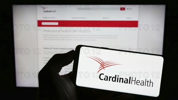 Stuttgart, Germany, 06-25-2023: Person holding mobile phone with logo of American healthcare company Cardinal Health Inc. on screen in front of web page. Focus on phone display, Europe