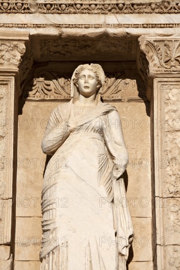 Ancient marble statue of a woman looks out under intricate archway copy space (statue is Sophia) (Goddess of Wisdom) (at the Celcus Library at Ephesus) (Turkey)