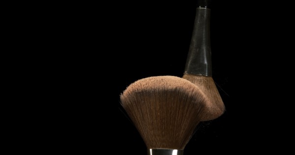 Make-up Brush spreading blush powder on black background