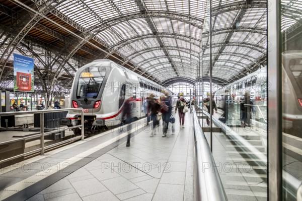 Travellers waiting for trains in a station concourse with an impressive roof, Leipzig Central Station