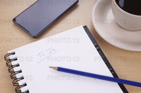 to-do list with note pad, pencil, mobile phone and cup of coffee on desk