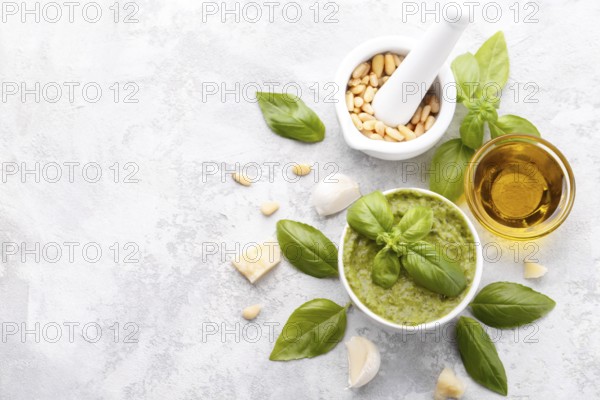 Pesto sauce and ingredients, cheese, basil, garlic, pine nuts, olive oil on grey stone background with copy space