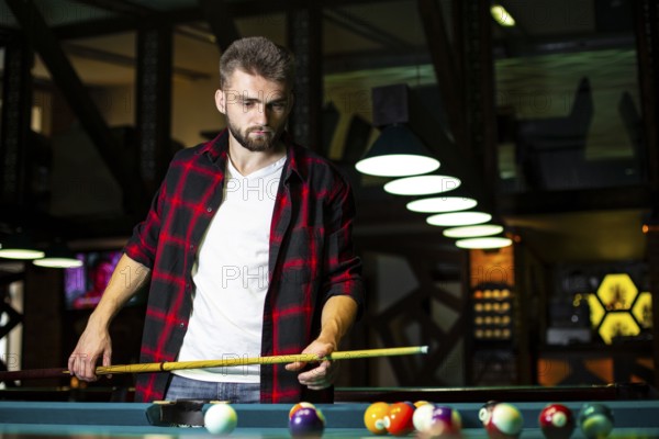 Medium shot guy with pool cue looking table