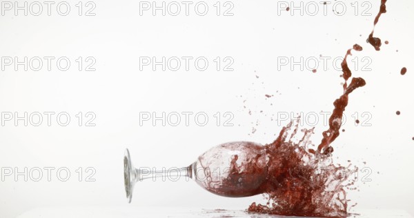 Glass of Red Wine Falling and Splashing against White Background