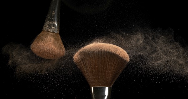 Make-up Brush spreading blush powder on black background