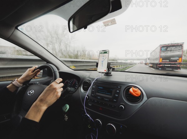 Inside view of a car with the driver's hands on the wheel and a mobile navigation system, A1 A8 highway near Milan, Italy, Europe