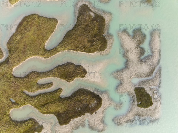 Patches of land appear while the tide is going out, in the marshland of the Bahía de Cádiz, aerial view, drone shot, Cádiz province; Andalusia; Spain