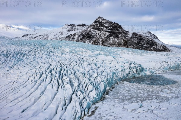 Snow-covered icebergs in the Fjallsarlon glacier lagoon, with the Öraefajökull glacier behind, drone shot, Sudurland, Iceland, Europe