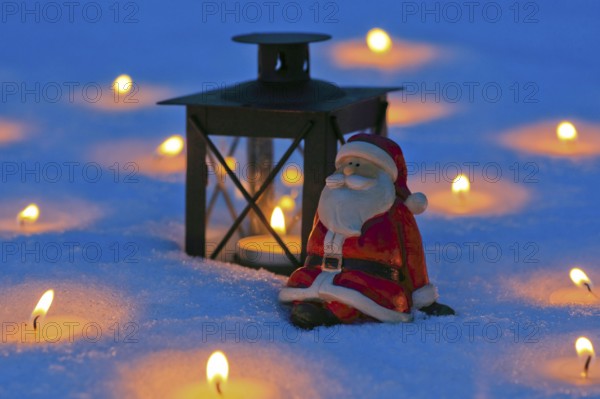 Santa Claus and lantern in the snow, with burning candles
