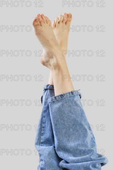 Bare female legs in boyfriend jean on grey background