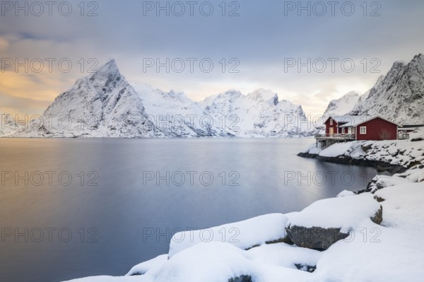 Red huts on the island of Sakrisøy, snow-covered mountains in the background, Sakrisoy, Reine, Lofoten, Norway, Europe