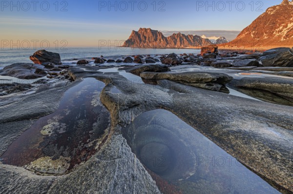 Rocky coast in front of steep mountains in the evening light, winter, the eye, Utakleiv, Vestvagoya, Lofoten, Norway, Europe
