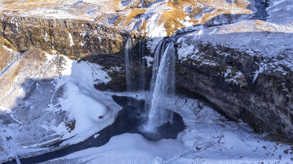 Aerial drone view of frozen Seljalandsfoss waterfall with snow in Iceland