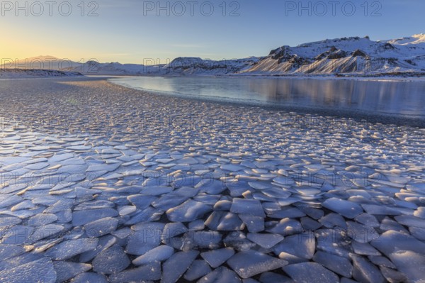 Ice floes on a lake in front of snowy mountains, sun, evening light, snow, winter, Snaefellsnes, Vesturland, Iceland, Europe