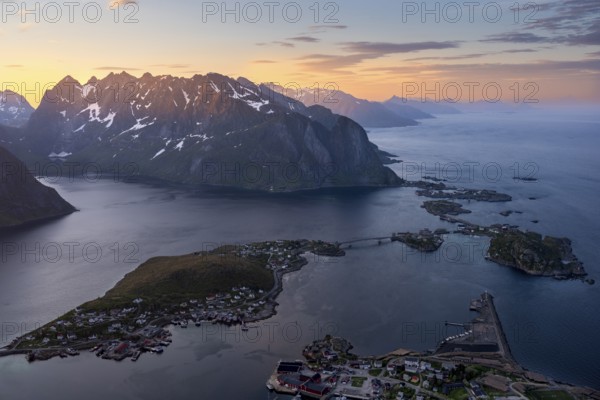 View from Reinebringen mountain to the village of Reine, Lilandstinden mountain and other mountains and the sea. At night during the midnight sun in good weather. Early summer. Reine, Moskenesoya, Lofoten, Norway, Europe