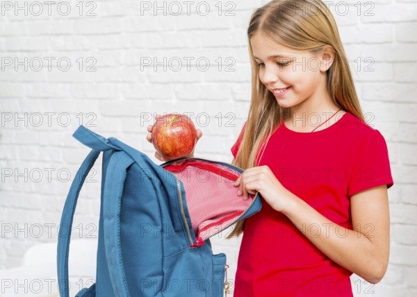 Happy girl putting apple backpack