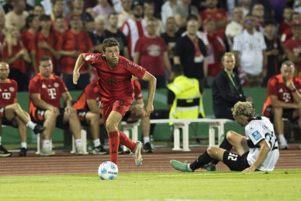 Football match, Thomas MÜLLER FC Bayern Munich left with the ball past Philipp STROMPF SSV Ulm on the ground, Donaustadion football stadium, Ulm, Germany, Europe