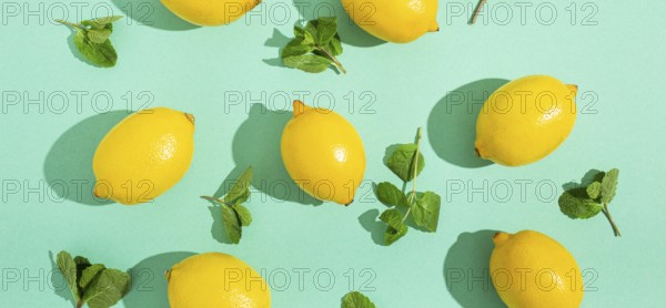Fresh yellow lemons with mint on minimal blue background on bright sun light with hard shadows pattern summer background flat lay from above, citrus food composition, space for text